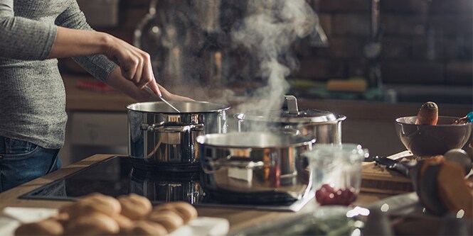 Frau bei der Zubereitung einer Mahlzeit in drei Töpfen
